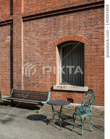 A view in front of a brick warehouse with a brick building and benches. 140893909