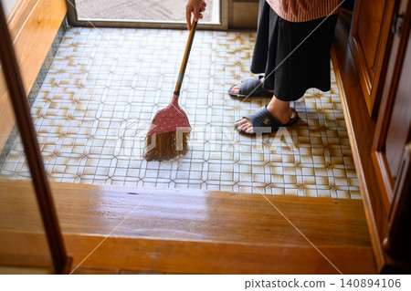 The back view of a woman holding a broom at the entrance. The back view of a woman holding a broom at the entrance. 140894106