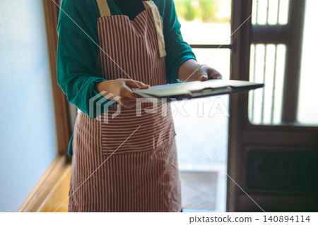 A woman in an apron hands out a neighborhood bulletin board. A woman in an apron hands out a neighborhood bulletin board. 140894114