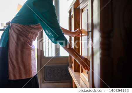 A woman returning home opens the shoe rack at the entrance of her family home. A woman returning home opens the shoe rack at the entrance of her family home. 140894123