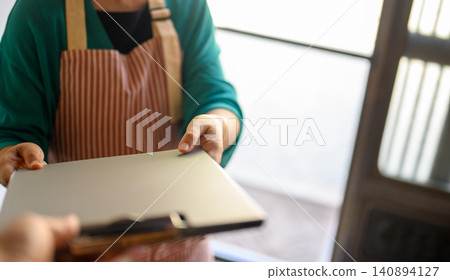 Handing over documents while wearing an apron Handing over documents while wearing an apron 140894127
