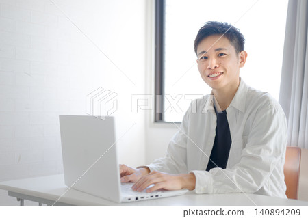 A smiling man working on his laptop. A smiling man working on his laptop. 140894209