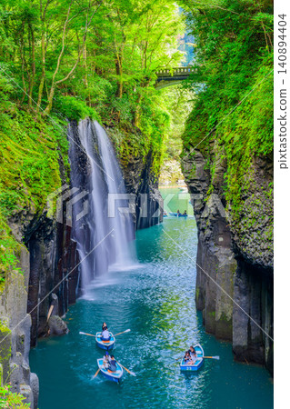 Autumn in Takachiho Gorge: A vertical composition view of the magnificent Manai Falls and a sightseeing boat from the waterfall viewing platform. Autumn in Takachiho Gorge: A vertical composition view of the magnificent Manai Falls and a sightseeing boat from the waterfall viewing platform. 140894404