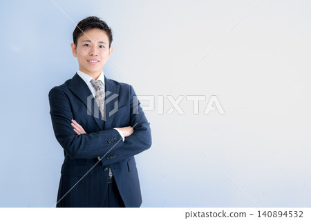 A young businessman stands with his arms crossed. A young businessman stands with his arms crossed. 140894532