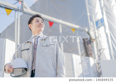一位年輕的工地主管面帶微笑地站在戶外。 140894535