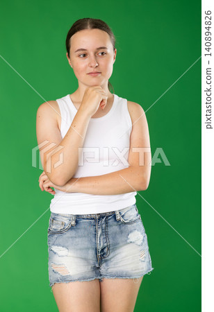 Teen european girl dressed in stylish shorts standing with thoughtful and sad-think look against green screen, chroma key compositing Teen european girl dressed in stylish shorts standing with thoughtful and sad-think look against green screen, chroma key compositing 140894826