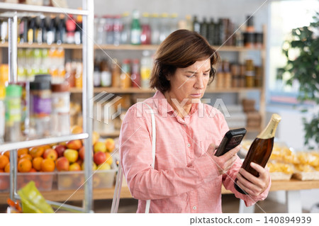 Female buyer scans QR code on beer label in grocery store Female buyer scans QR code on beer label in grocery store 140894939