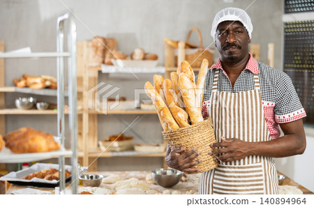 Professional baker presenting fresh french baguettes in bakery Professional baker presenting fresh french baguettes in bakery 140894964