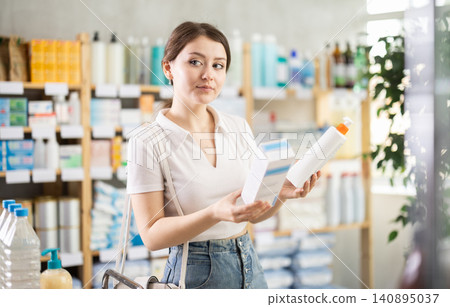 Girl in summer clothes choosing skin cream at drugstore Girl in summer clothes choosing skin cream at drugstore 140895037