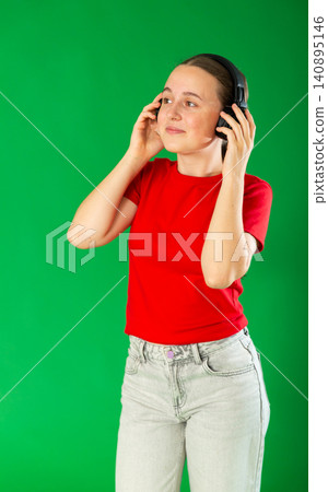 Teenage girl listening to music and dancing in front of green screen Teenage girl listening to music and dancing in front of green screen 140895146