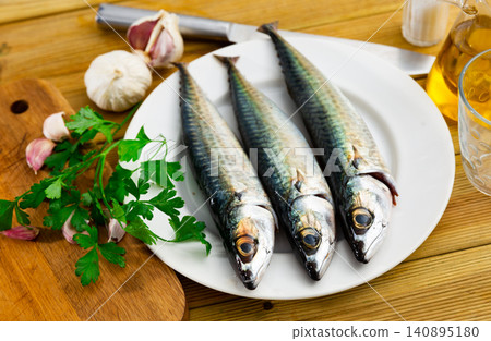 Whole mackerel carcasses, parsley, garlic are on wooden background 140895180