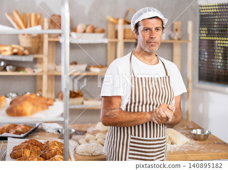 Caucasian man cook-baker stands at table in kitchen of bakery 140895182