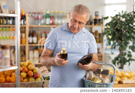 Senior man hold bottle and choose consider beer in store Senior man hold bottle and choose consider beer in store 140895183