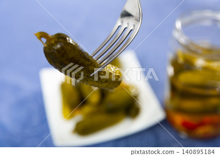 One pickled cucumber on fork, homemade preserves One pickled cucumber on fork, homemade preserves 140895184