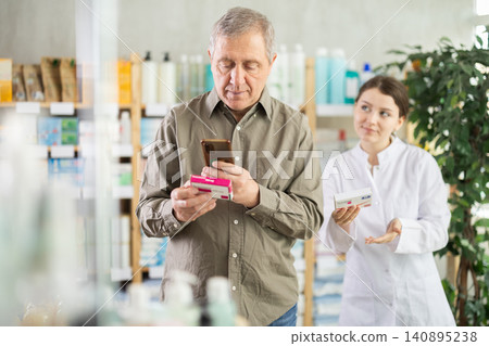 Mature man scans QR code on box pills label. Female pharmacist offers to choose box pills Mature man scans QR code on box pills label. Female pharmacist offers to choose box pills 140895238