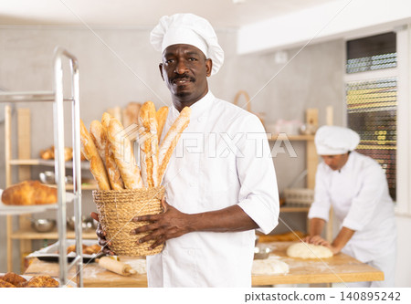 Adult man baker with basket of baguettes Adult man baker with basket of baguettes 140895242