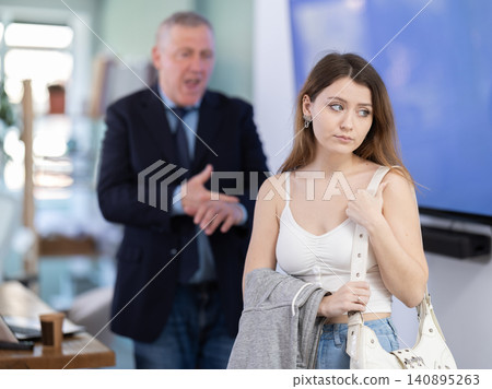 Elderly man scolding female colleague for being late to office 140895263