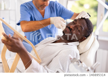 African American patient looking in mirror during consultation of cosmetologist African American patient looking in mirror during consultation of cosmetologist 140895314