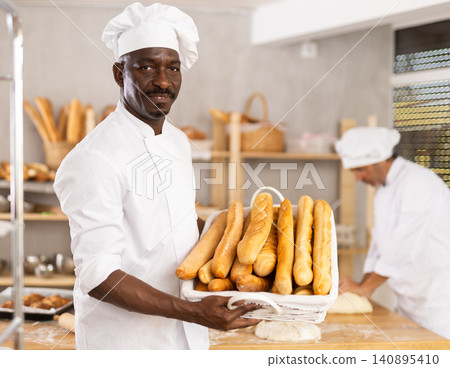 Adult man baker with basket of baguettes 140895410