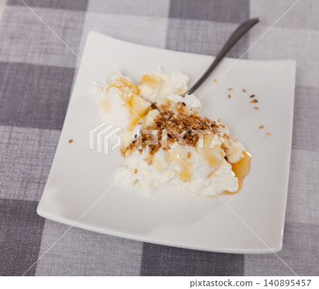 Close-up cottage cheese in plate. Homemade curd cheese served with sesame seeds and honey. Catalan mato con miel 140895457