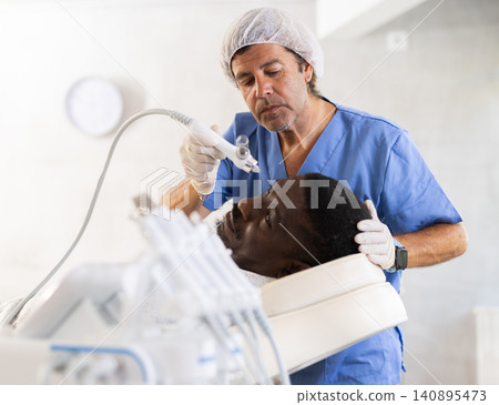 African man undergoes facial skin moisturizing procedure with hydrogen-oxygen hydrating nozzle African man undergoes facial skin moisturizing procedure with hydrogen-oxygen hydrating nozzle 140895473