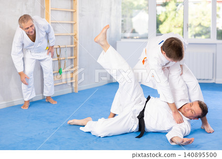 Focused guy practicing judo techniques in sparring with male opponent Focused guy practicing judo techniques in sparring with male opponent 140895500