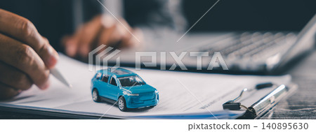 Person signing buying car contract for vehicle purchase and insurance, close up of hand with pen on document, small blue toy car on clipboard, laptop in background for finance Person signing buying car contract for vehicle purchase and insurance, close up of hand with pen on document, small blue toy car on clipboard, laptop in background for finance 140895630