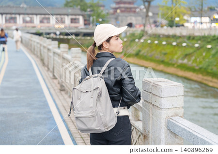 Happy woman traveler travel in Dujiangyan city. Tourist sightseeing Guanxian Ancient City near Chengdu. Landmark and popular for tourism attraction in Sichuan, China Happy woman traveler travel in Dujiangyan city. Tourist sightseeing Guanxian Ancient City near Chengdu. Landmark and popular for tourism attraction in Sichuan, China 140896269