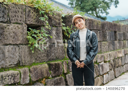 Happy woman traveler travel in Dujiangyan city. Tourist sightseeing the Ming City Wall at Guanxian Ancient City near Chengdu. Landmark and popular for tourism attraction in Sichuan, China Happy woman traveler travel in Dujiangyan city. Tourist sightseeing the Ming City Wall at Guanxian Ancient City near Chengdu. Landmark and popular for tourism attraction in Sichuan, China 140896270