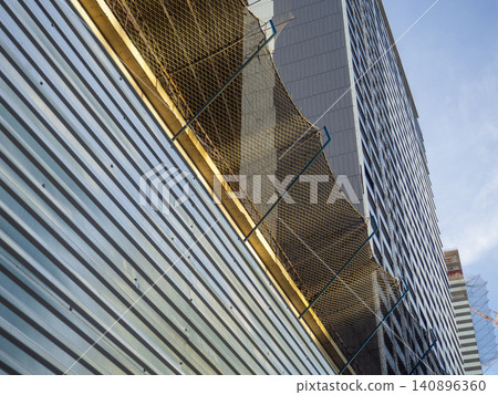 Glass facade of a house under construction with open windows. Construction safety net. Geometry in architecture. Glass facade of a house under construction with open windows. Construction safety net. Geometry in architecture. 140896360