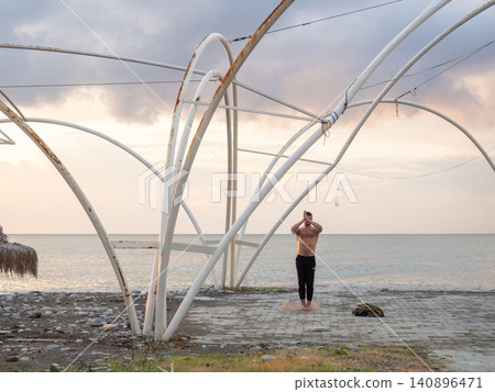 man does yoga in the fall. On the seashore. Resort out of season. Healthy lifestyle. Concept man does yoga in the fall. On the seashore. Resort out of season. Healthy lifestyle. Concept 140896471