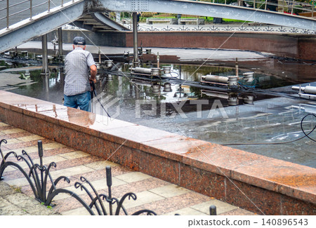 Empty fountain in a city park. Draining the fountain. Cleaning the fountain with a hose. Empty fountain in a city park. Draining the fountain. Cleaning the fountain with a hose. 140896543