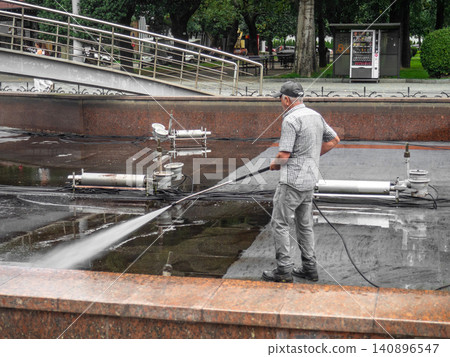 Empty fountain in a city park. Dehumidification. Cleaning the fountain with a hose. The device of the fountain. Pipes for water supply. Water hoses. Modern technologies. Infrastructure maintenance. Empty fountain in a city park. Dehumidification. Cleaning the fountain with a hose. The device of the fountain. Pipes for water supply. Water hoses. Modern technologies. Infrastructure maintenance. 140896547