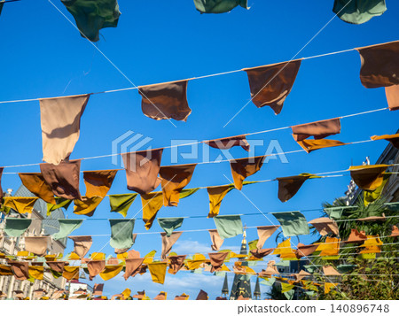 Flags over the street. City celebration concept. Warm colors. Scenery over the street. Flags over the street. City celebration concept. Warm colors. Scenery over the street. 140896748