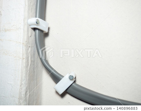 Fastening the wire to the wall. Ceiling mounting. Electric cord in the apartment. 220 volt. Fastening the wire to the wall. Ceiling mounting. Electric cord in the apartment. 220 volt. 140896883