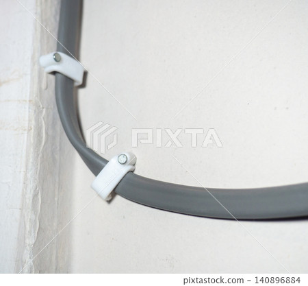 Fastening the wire to the wall. Ceiling mounting. Electric cord in the apartment. 220 volt. Fastening the wire to the wall. Ceiling mounting. Electric cord in the apartment. 220 volt. 140896884