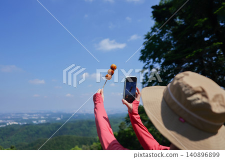 A woman taking a photo of dango (rice dumplings) with her smartphone on Mount Takao. 140896899