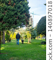 A man walks a large dog in the park. Back view. Retreating figures of a man and a dog. Vacation with a pet at the resort. 140897018