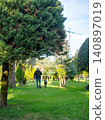 A man walks a large dog in the park. Back view. Retreating figures of a man and a dog. Vacation with a pet at the resort. 140897019