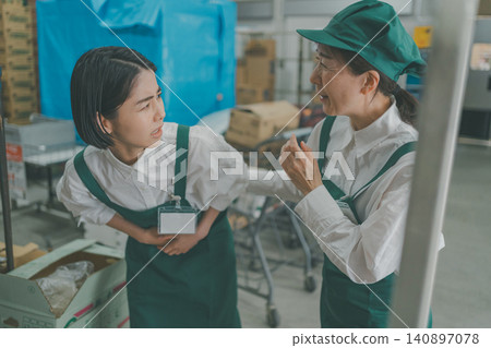 A senior staff member helps a young female staff member who is feeling unwell in the back room. 140897078