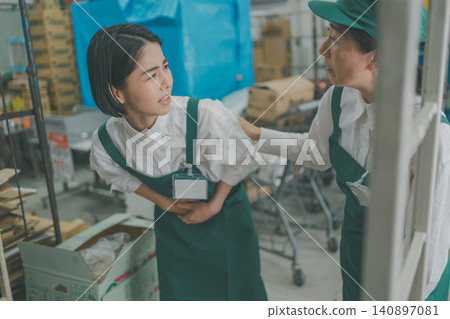 A senior staff member helps a young female staff member who is feeling unwell in the back room. 140897081