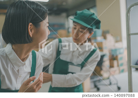 A senior staff member worries about a female staff member who is troubled in the back room of the supermarket. A senior staff member worries about a female staff member who is troubled in the back room of the supermarket. 140897088