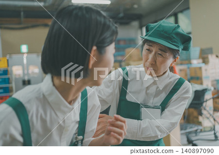 A senior staff member worries about a junior colleague in the back room of a supermarket. A senior staff member worries about a junior colleague in the back room of a supermarket. 140897090