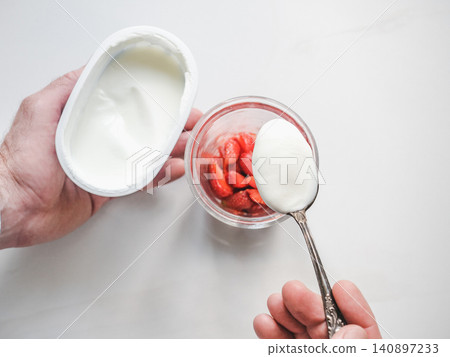 Hands stirring strawberry yogurt with a spoon Hands stirring strawberry yogurt with a spoon 140897233