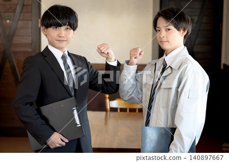 一名身穿西裝的男子和一名工人正在展示他們的合作精神。 一名身穿西裝的男子和一名工人正在展示他們的合作精神。 140897667