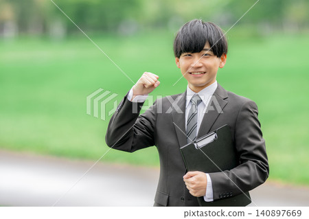 A young businessman makes a triumphant gesture outdoors. A young businessman makes a triumphant gesture outdoors. 140897669