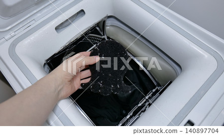 Hand holding a lint catcher full of lint over a washing machine 140897704
