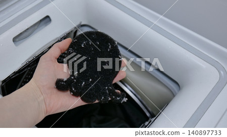 Hand holding a lint-covered laundry lint catcher from a washing machine Hand holding a lint-covered laundry lint catcher from a washing machine 140897733