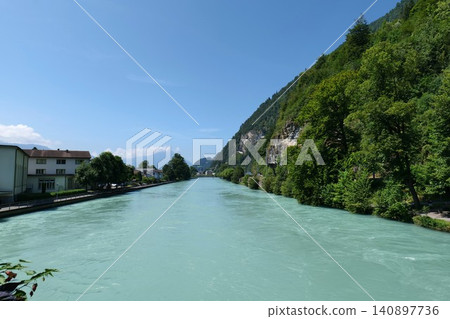 Scenic Turquoise River in a Mountain Valley with a Town. switzerland Scenic Turquoise River in a Mountain Valley with a Town. switzerland 140897736