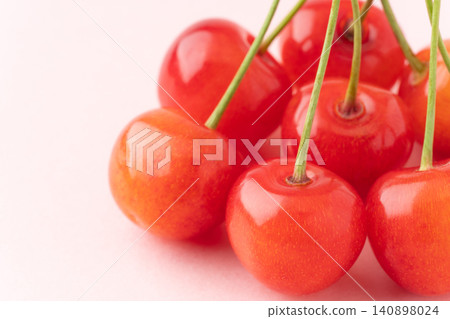 A close-up of a cherry (Sato Nishiki) against a light pink background. A close-up of a cherry (Sato Nishiki) against a light pink background. 140898024
